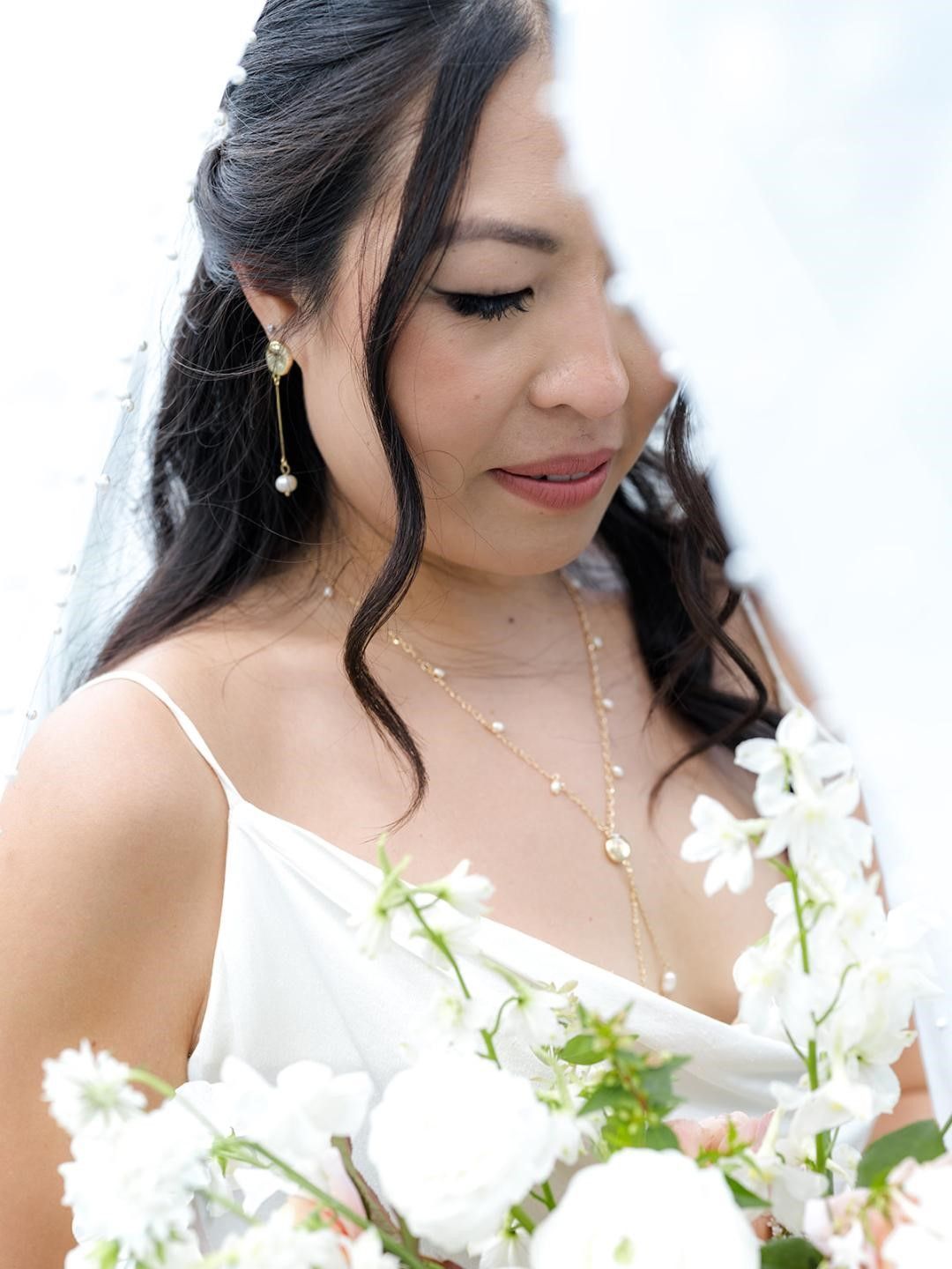 A woman in a white dress is holding a bouquet of white flowers.