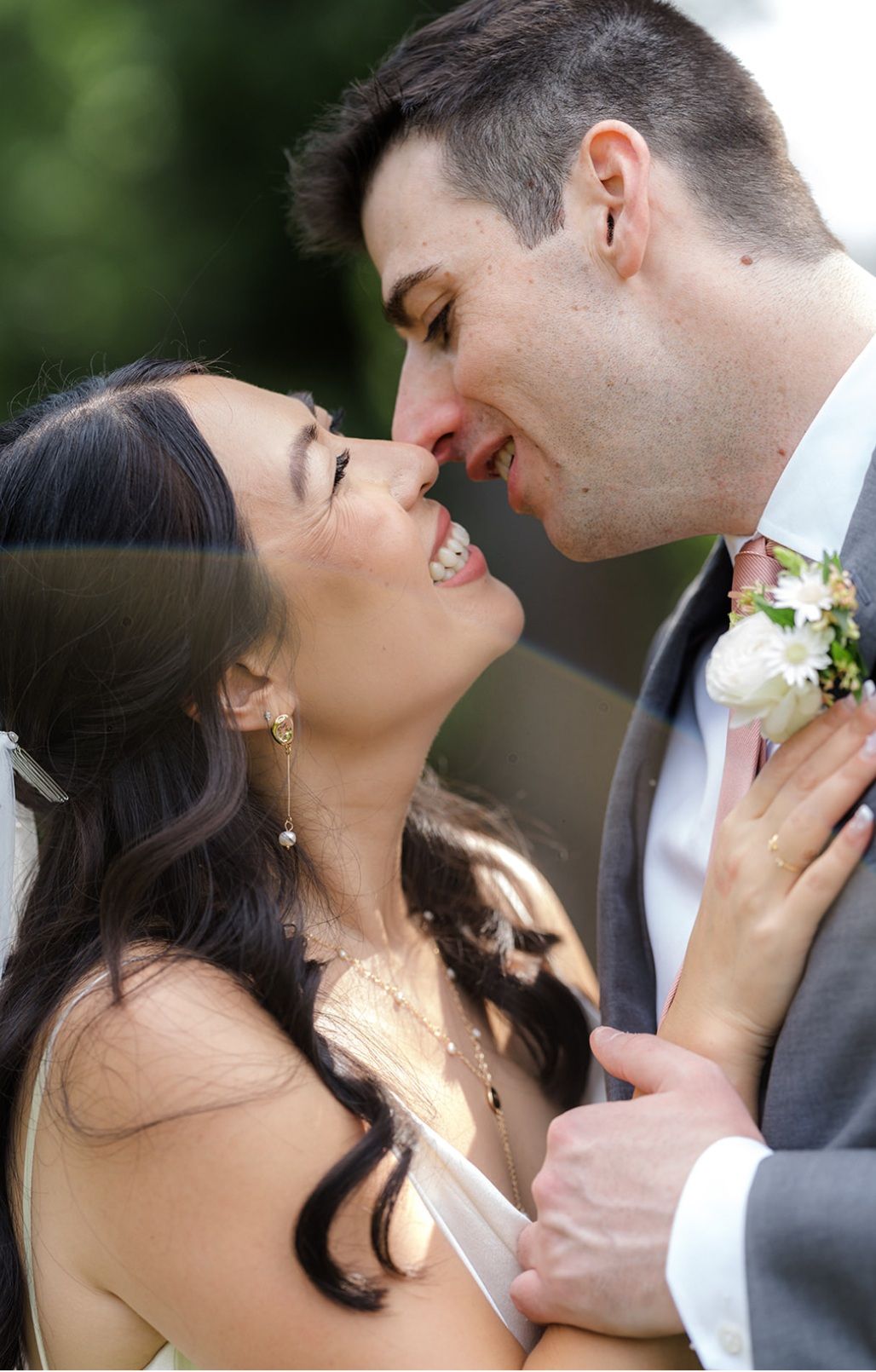 A bride and groom are kissing in front of a window