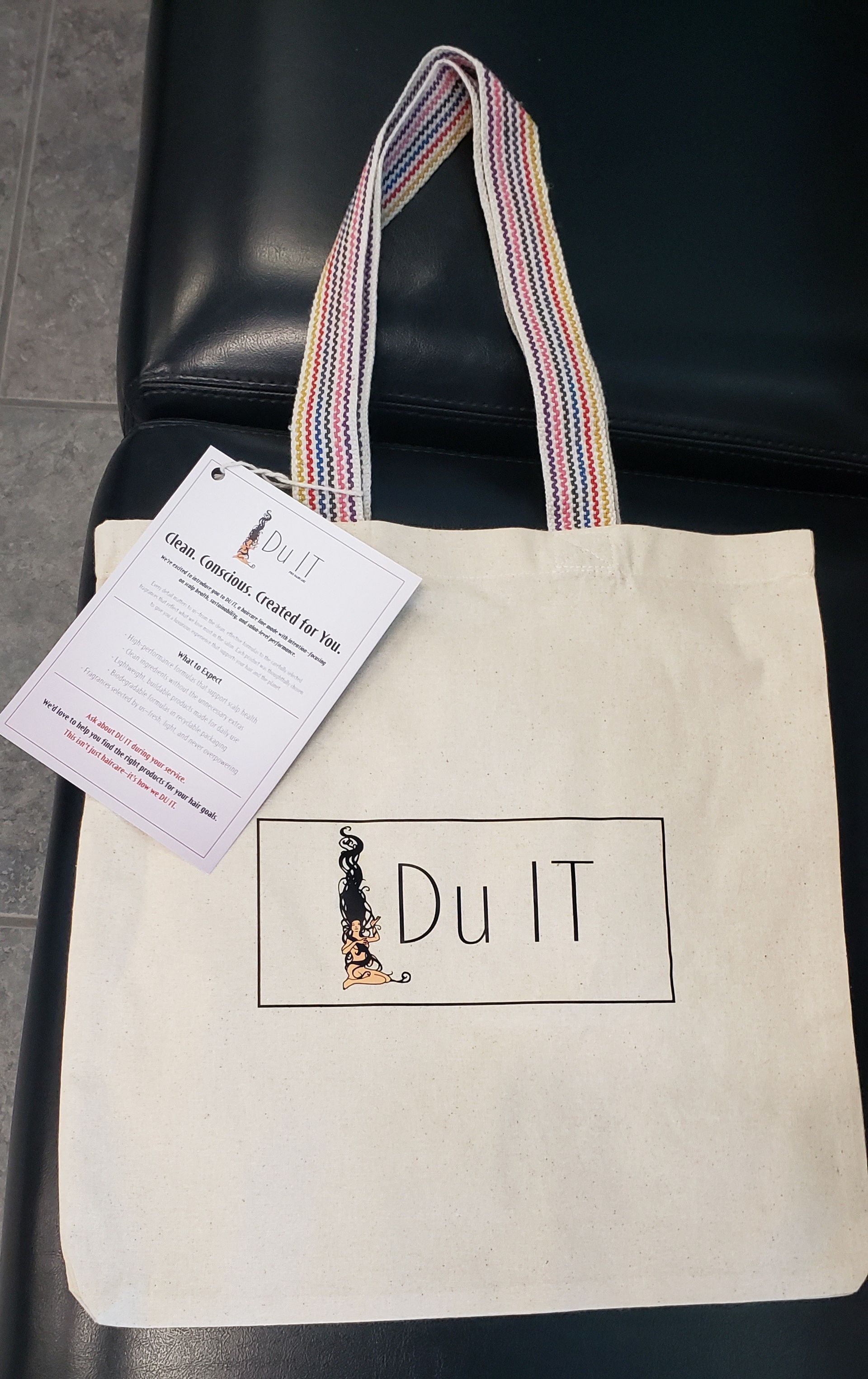 A white tote bag with a tag that says Du IT.