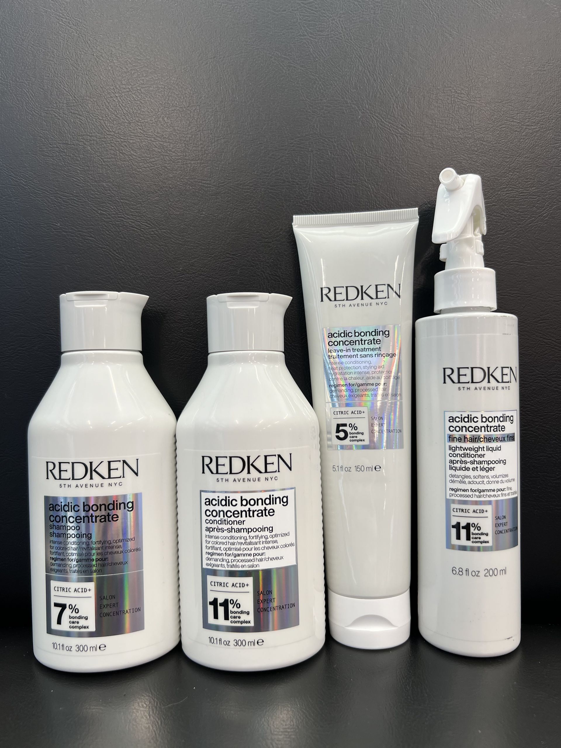 Four bottles of redken hair products are lined up on a table.