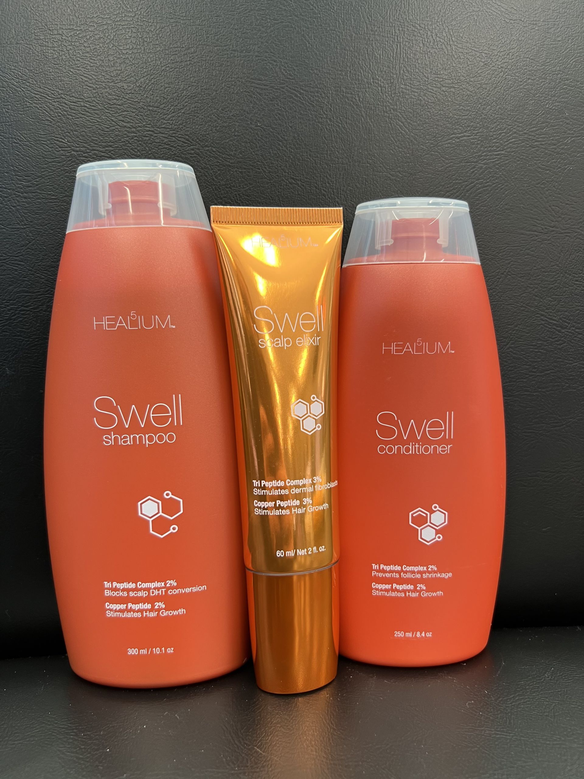 Three orange bottles of shampoo and a tube of lip balm