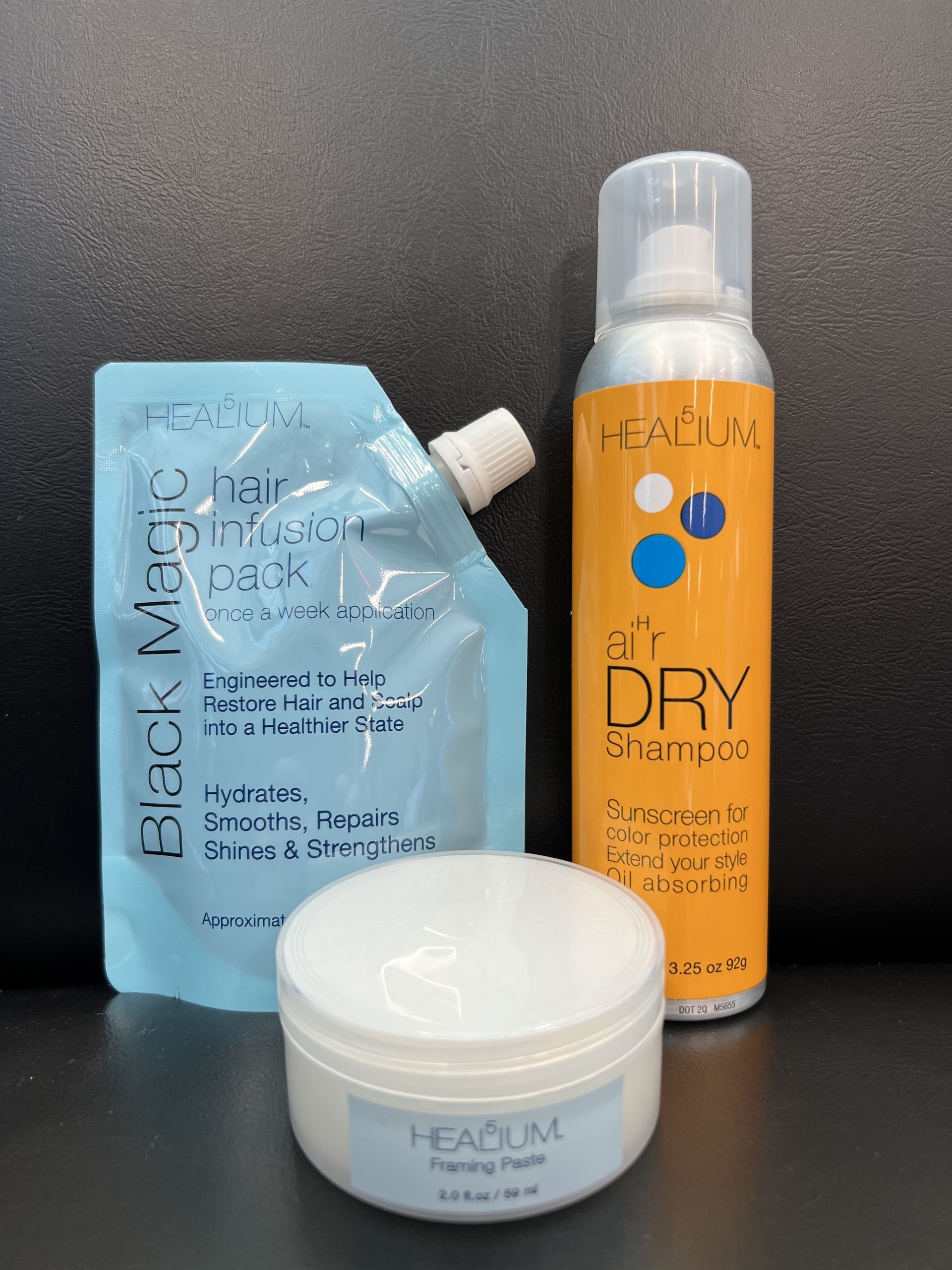 A bottle of air dry shampoo next to a bottle of back magic hair mask