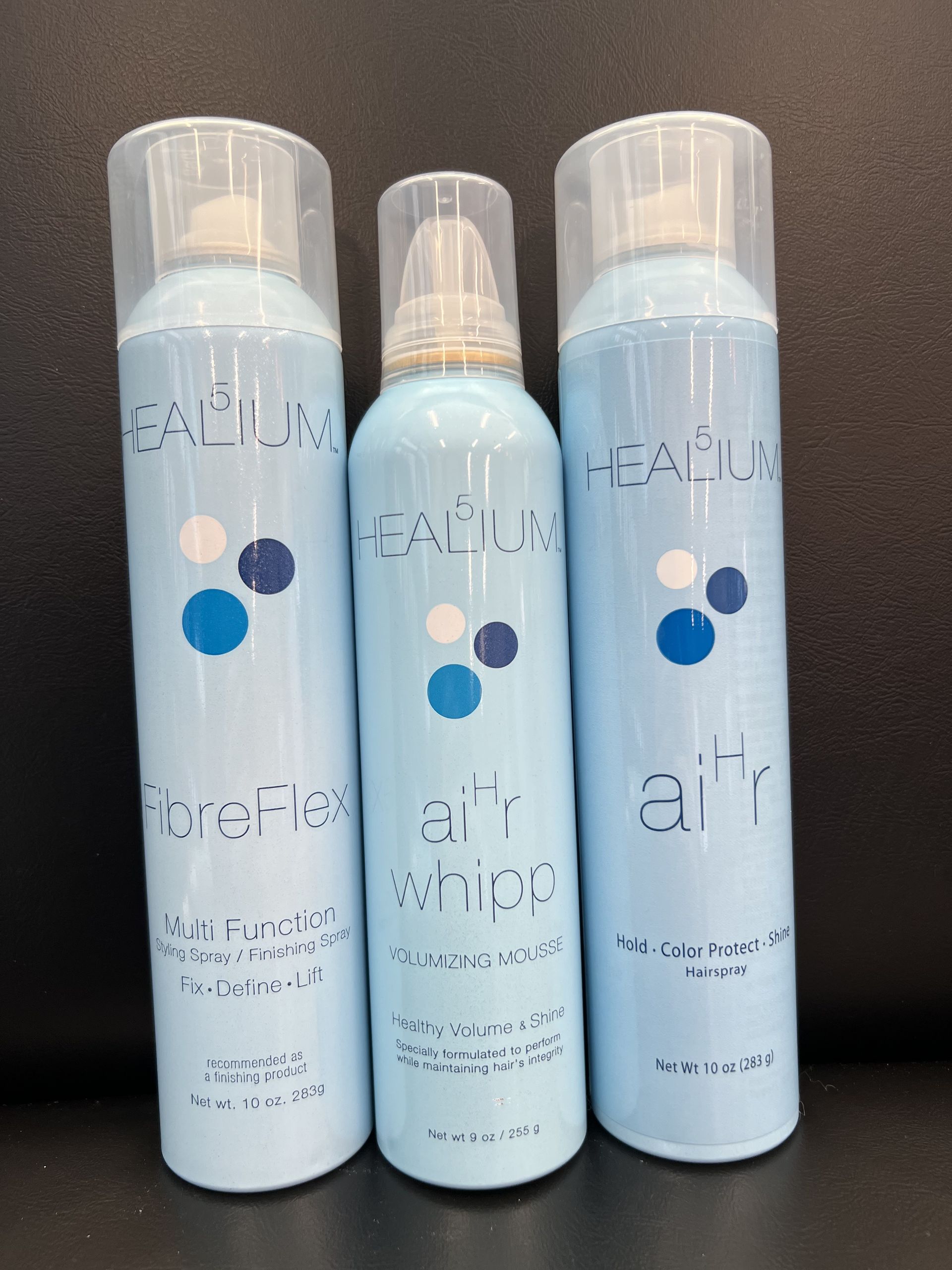 Three bottles of spray sitting next to each other on a table.