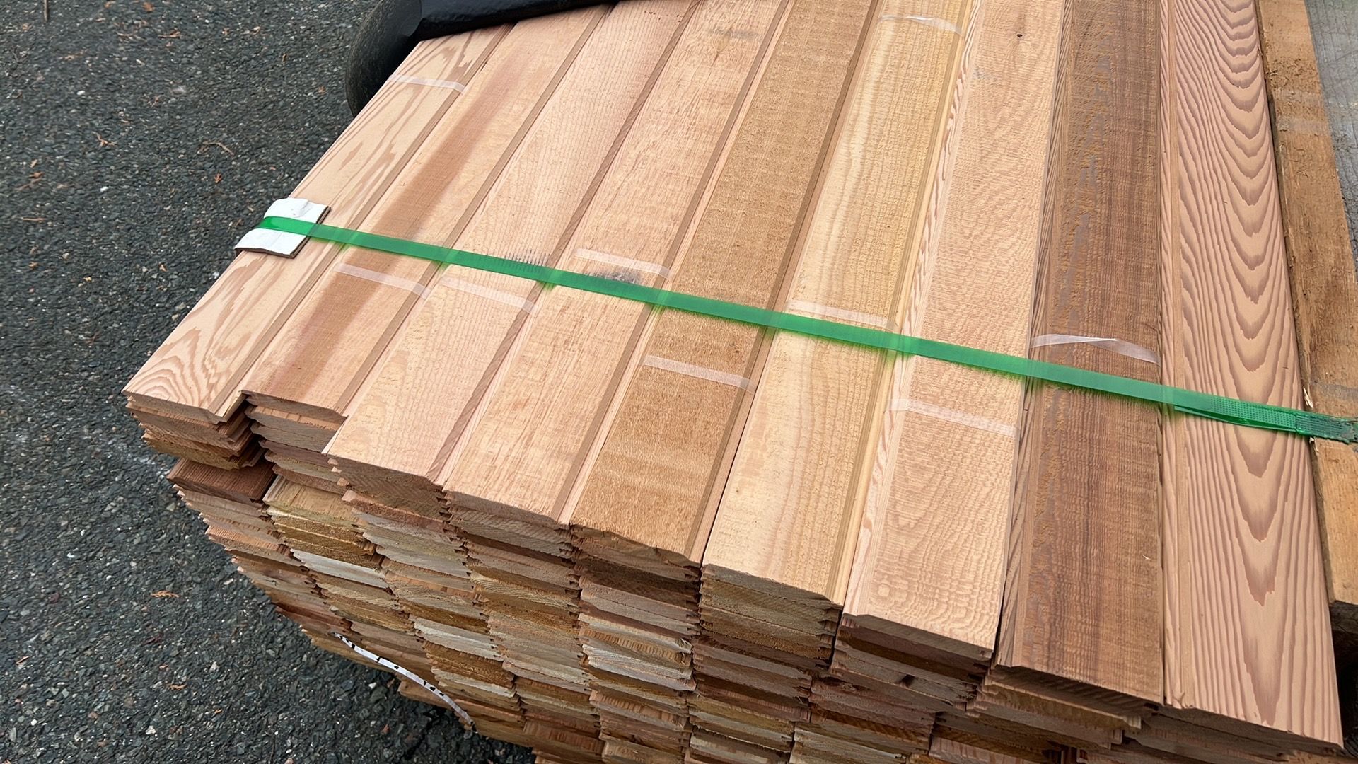 A stack of wood is tied together with a green tape.