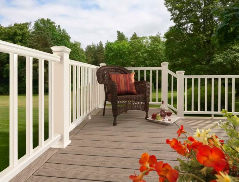 A wicker chair is sitting on a deck with a white railing.