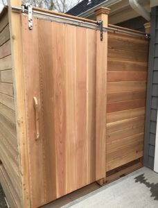 A wooden fence with a sliding barn door attached to it.
