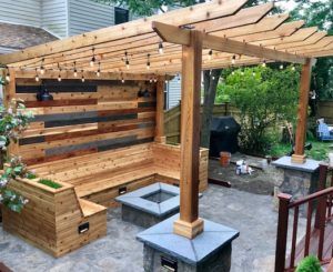 A wooden pergola with a fire pit in the backyard.