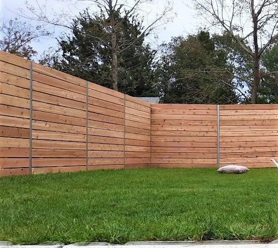 A wooden fence surrounds a lush green yard.