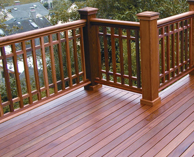 A wooden deck with a wooden railing and a view of a city