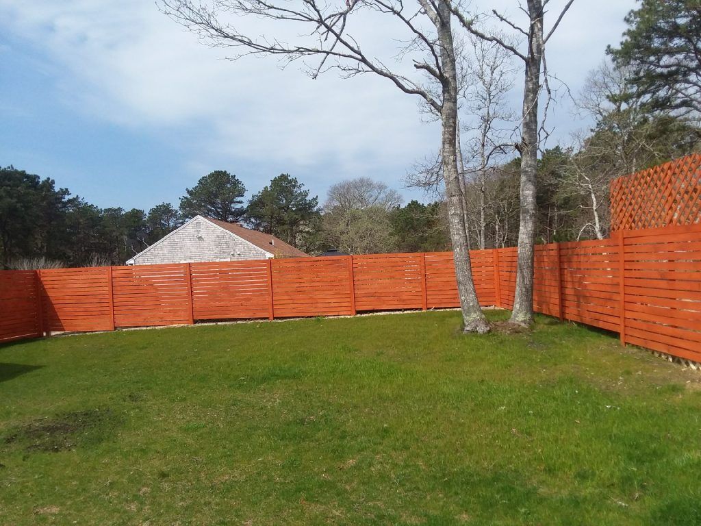 A wooden fence surrounds a lush green yard