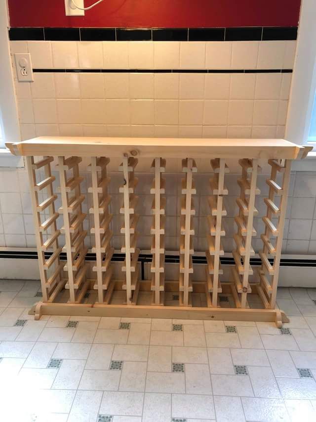 A wooden wine rack is sitting on a tiled floor in a kitchen.