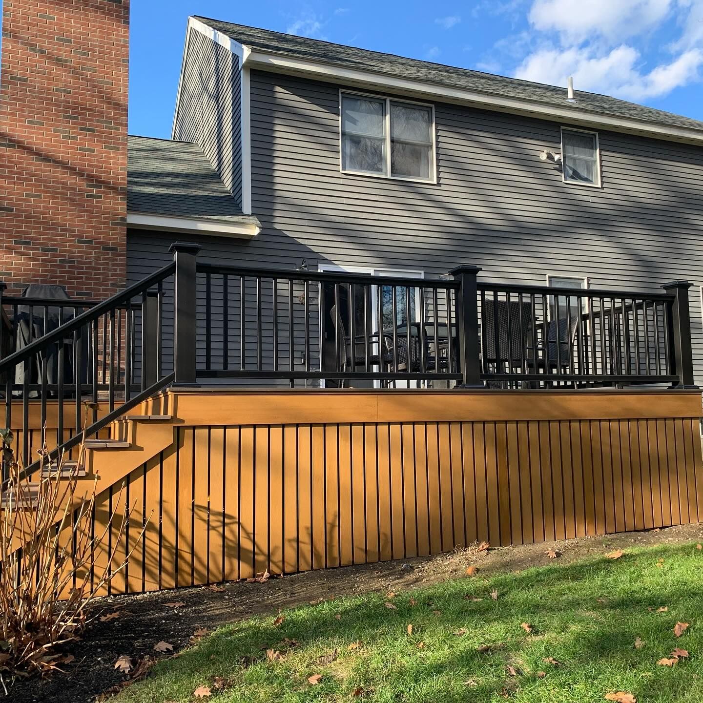 A deck with stairs leading up to it is in front of a house.