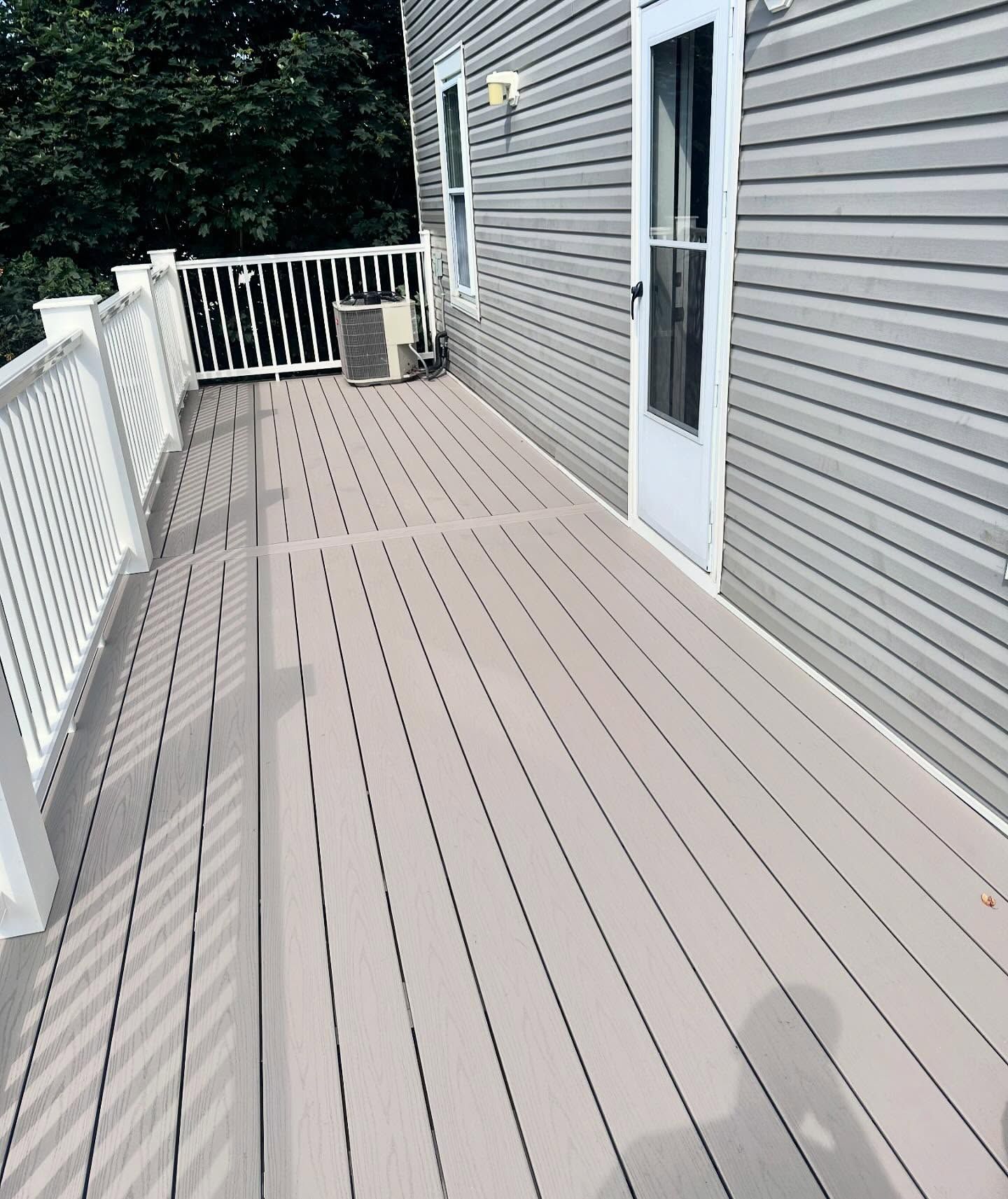 A large deck with a white railing and a white door