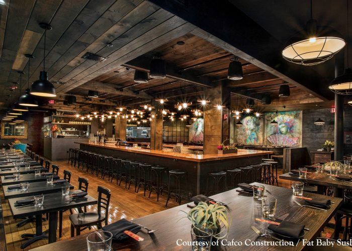 A restaurant with tables and chairs and a long bar.