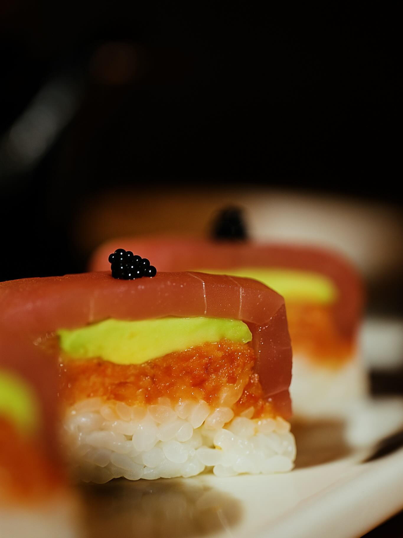 Sushi roll with tuna, avocado, and roe, topped with black caviar.