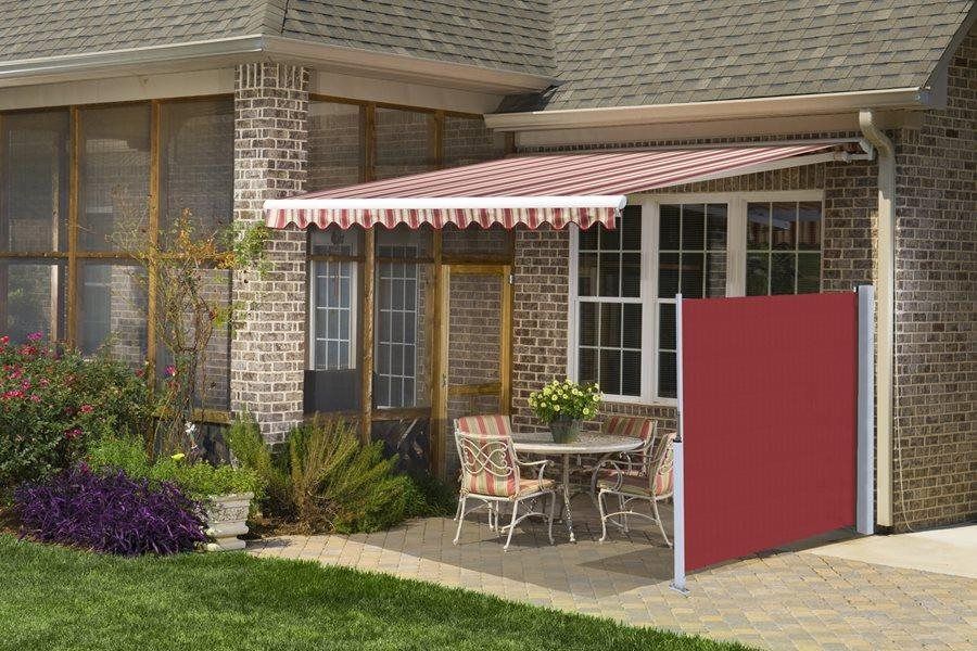 a brick house with a red awning over a patio with a table and chairs .