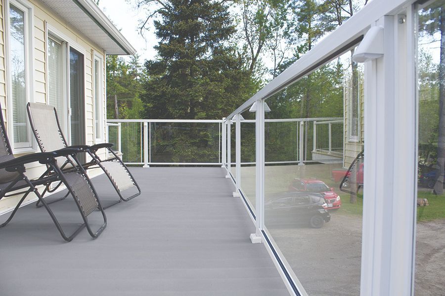 a balcony with a glass railing and chairs on it