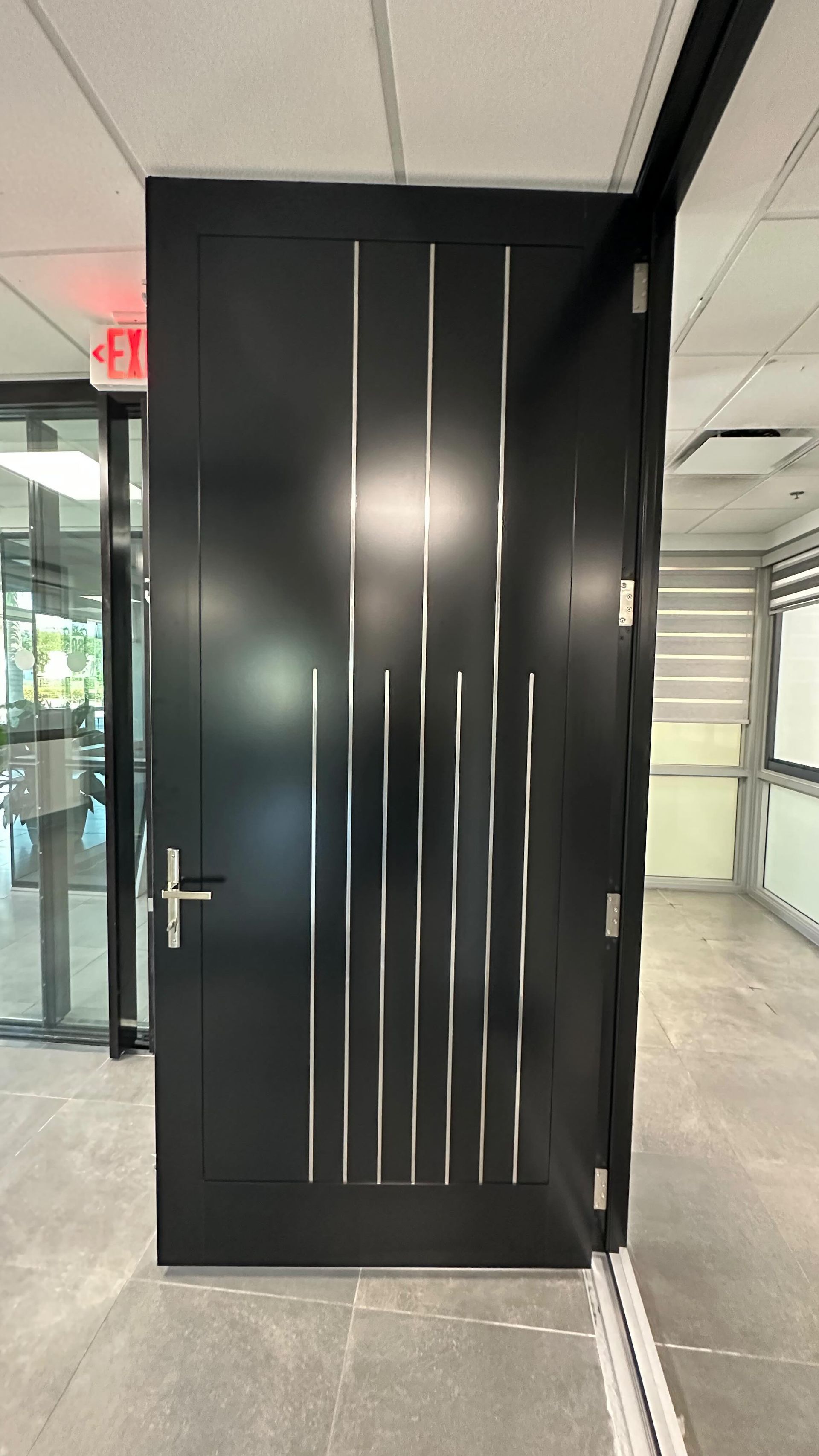 A black door with a design on it is in a hallway.