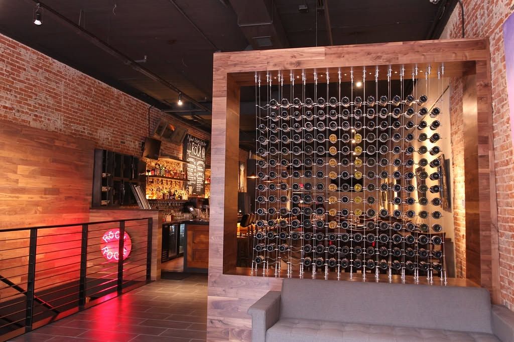 Modern wine cellar with brick walls, hanging glassware, and warm ambient lighting