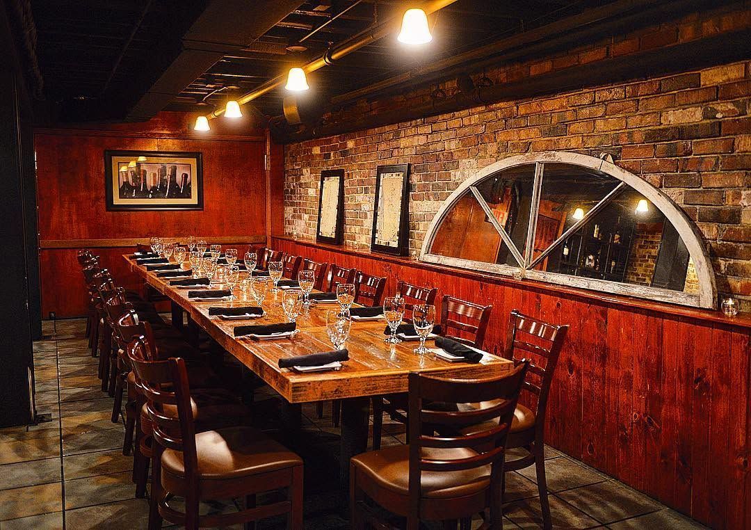 Cozy brick-walled restaurant booth with a long wooden table and warm overhead lights