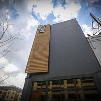 Modern building facade with a vertical wooden accent panel against a cloudy sky