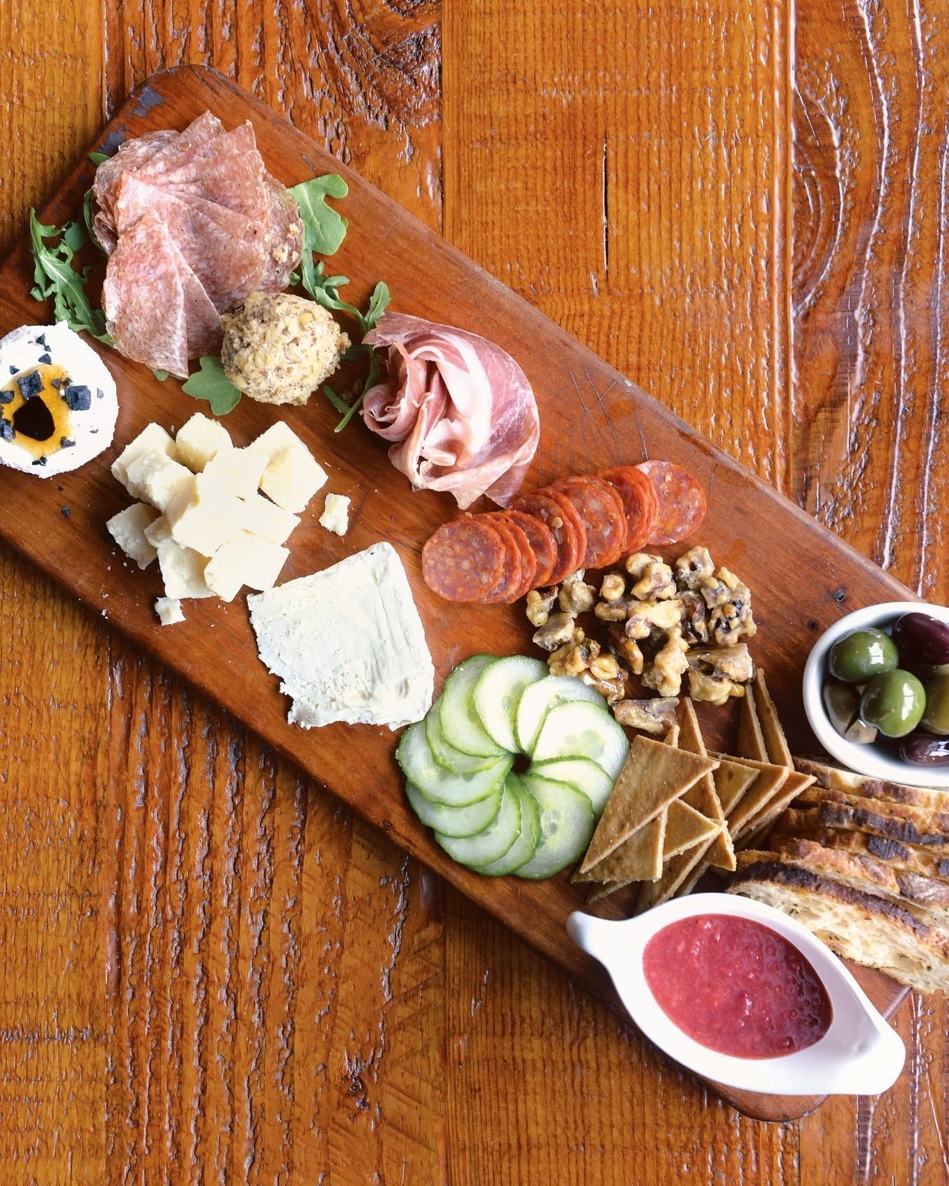 Charcuterie board with cheeses, meats, olives, nuts, fruit, and crackers on a wooden table