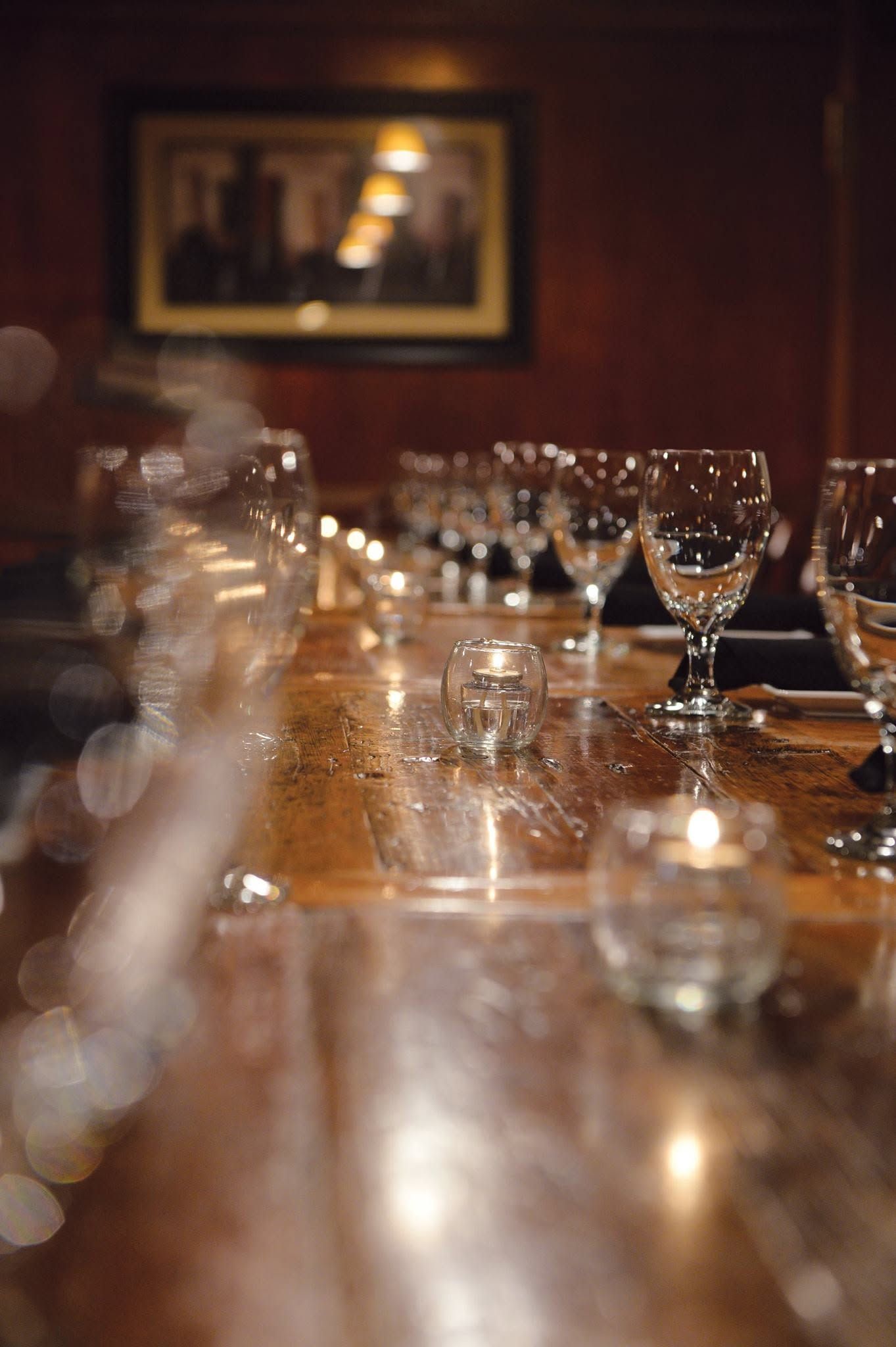 Long dining table set with glassware in a warmly lit restaurant or banquet room