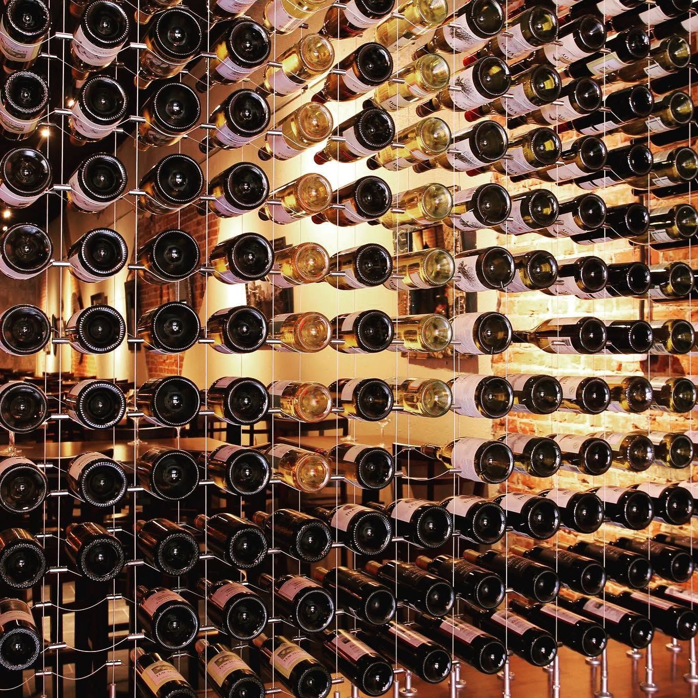 Wall-mounted wine rack filled with bottles, seen from above in a warm-toned cellar