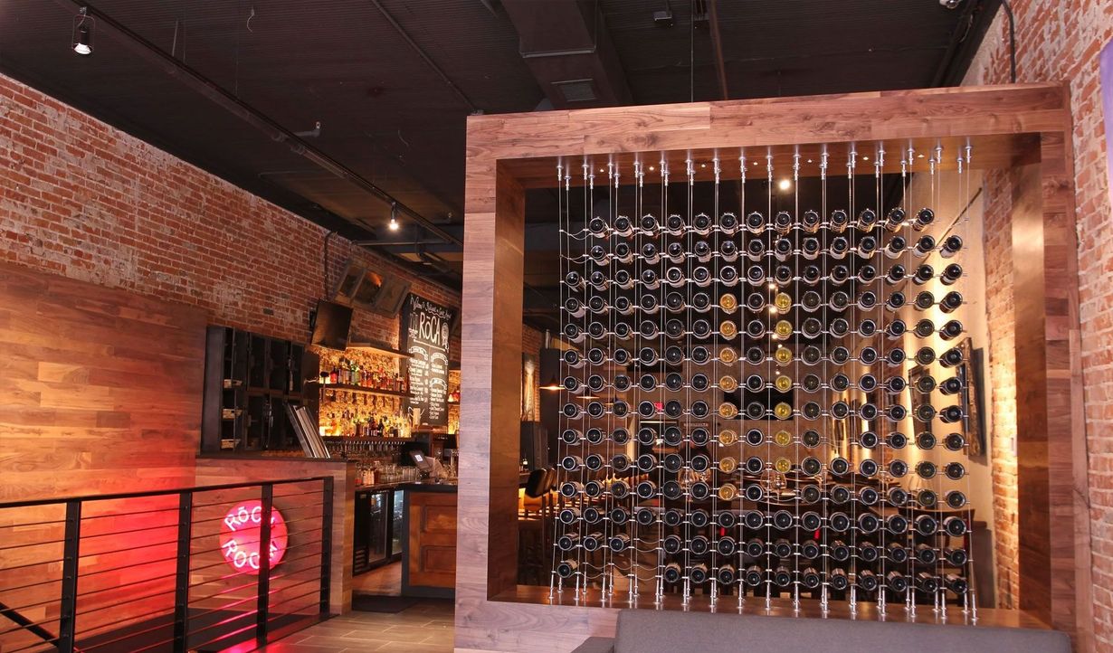 Brick-walled wine cellar with a large wooden wine rack filled with bottles