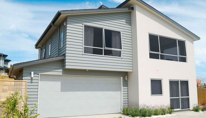 Two-story beige house with gray trim, double garage, and large windows under a blue sky