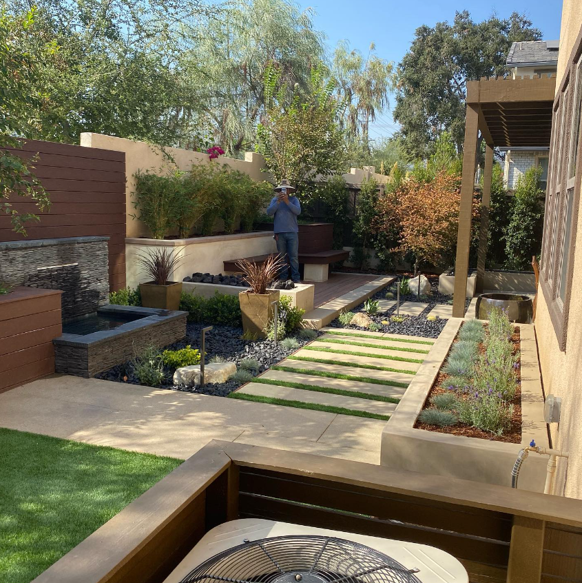 Landscape Project is finished in La Verne. Trees, bushes and a person in the background taking a picture.