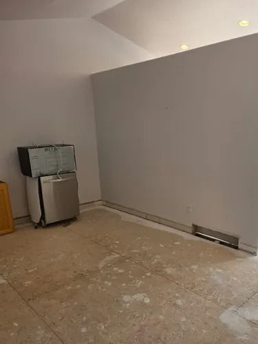 Empty room with gray walls, tiled floor, and a small appliance in the left corner.