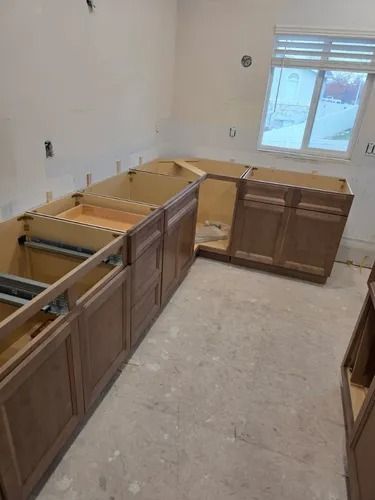 Unfinished kitchen with wood cabinets, bare countertops, and a window in the back wall.