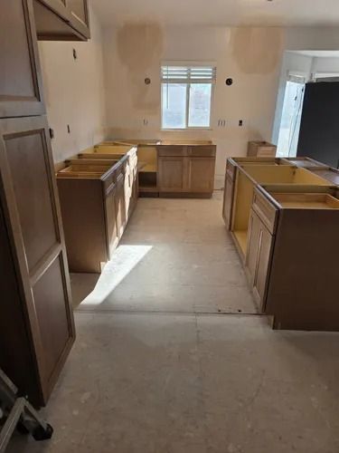 Empty kitchen with unfinished cabinets, a window, and sunlight on the floor