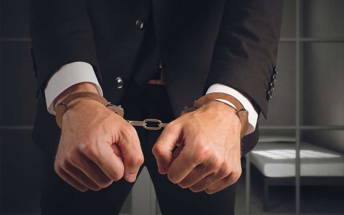 A man in a suit and tie is handcuffed.