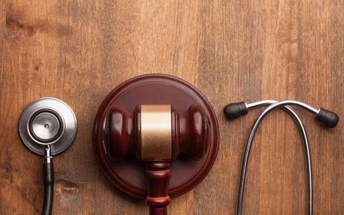 A judge 's gavel , stethoscope and a stethoscope are on a wooden table.