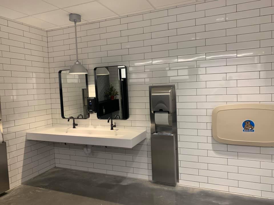A bathroom with a sink , mirrors , and a changing table.