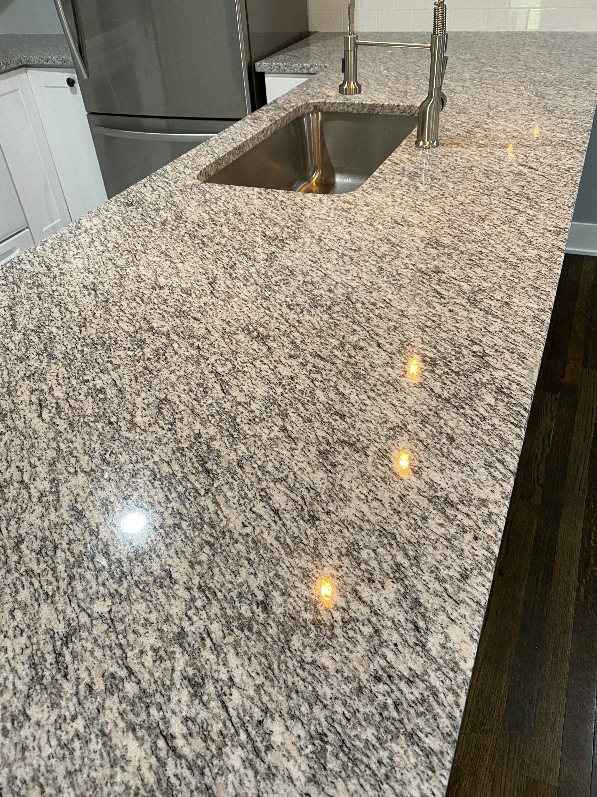 A kitchen with granite counter tops and a stainless steel sink.