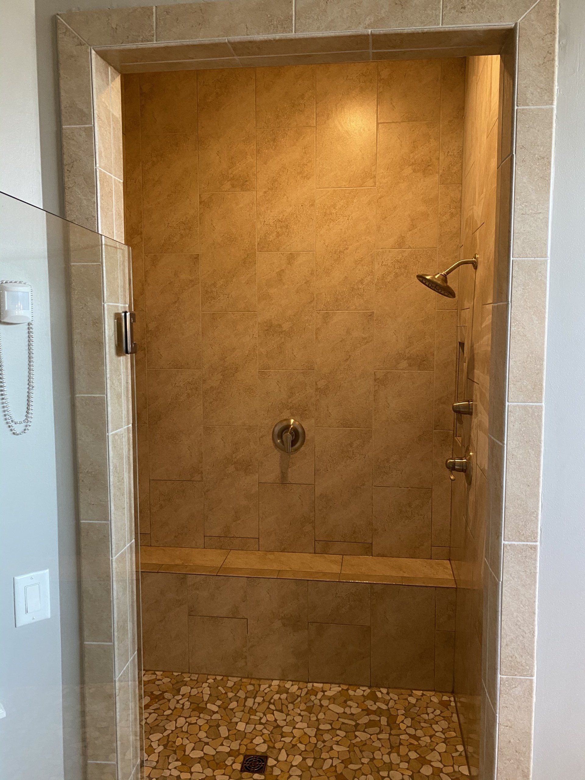 A bathroom with a walk in shower and a bench.