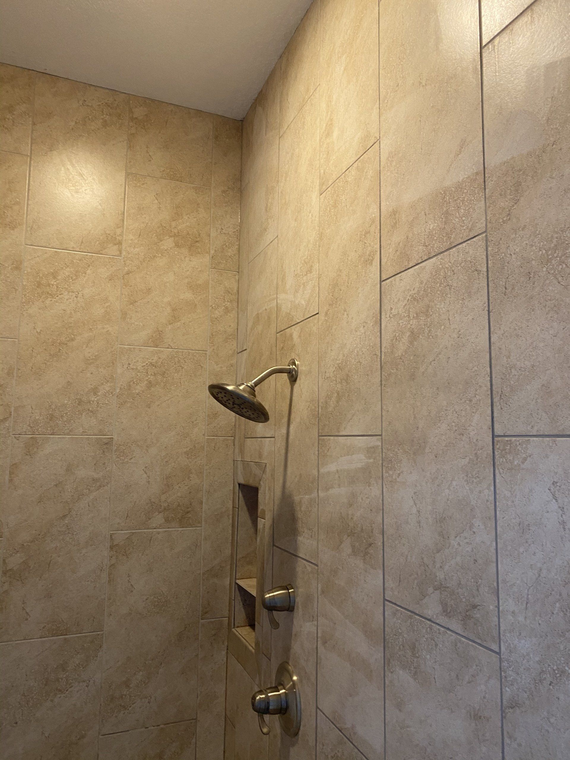 A shower head is hanging on a tiled wall in a bathroom.