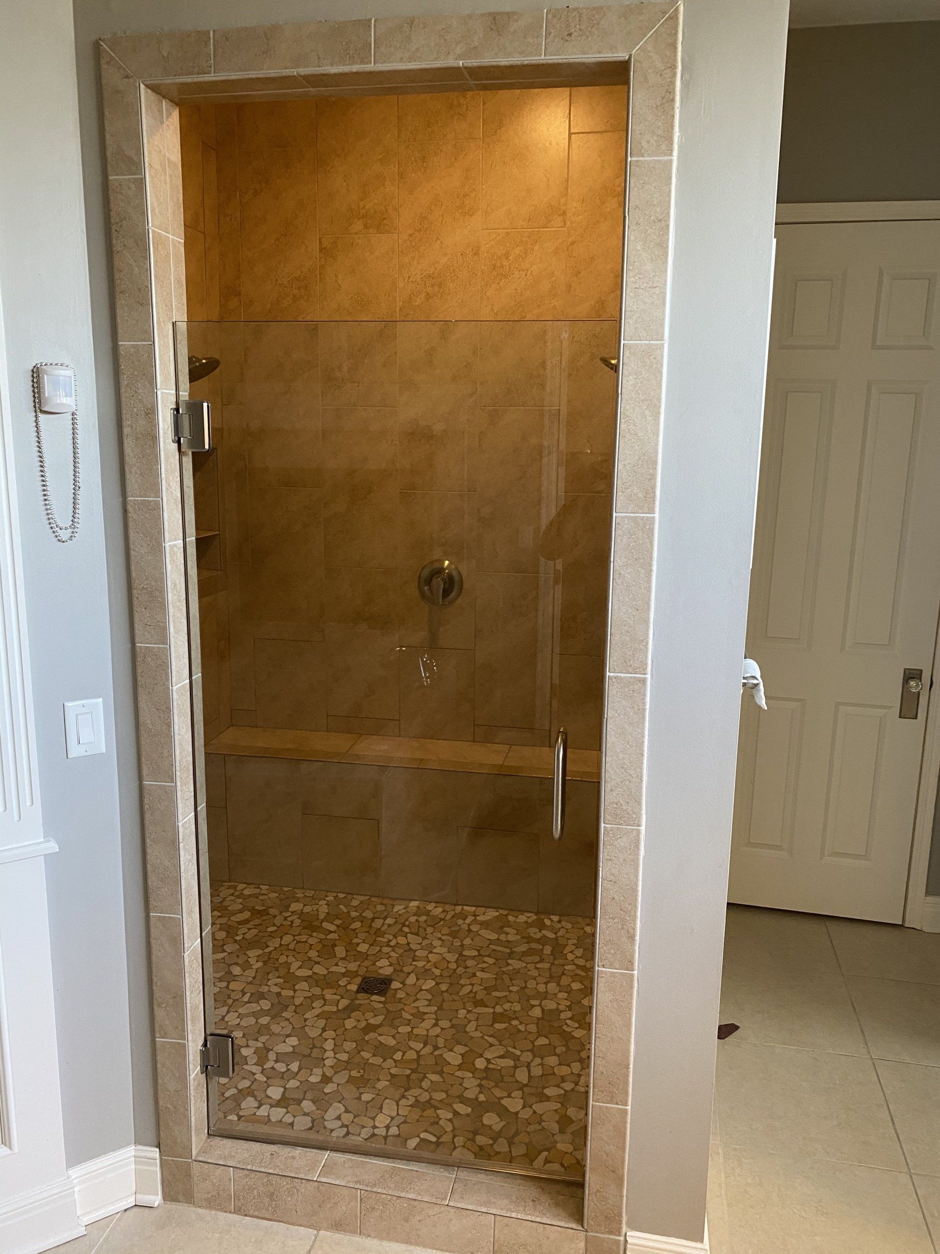 A bathroom with a walk in shower with a glass door.