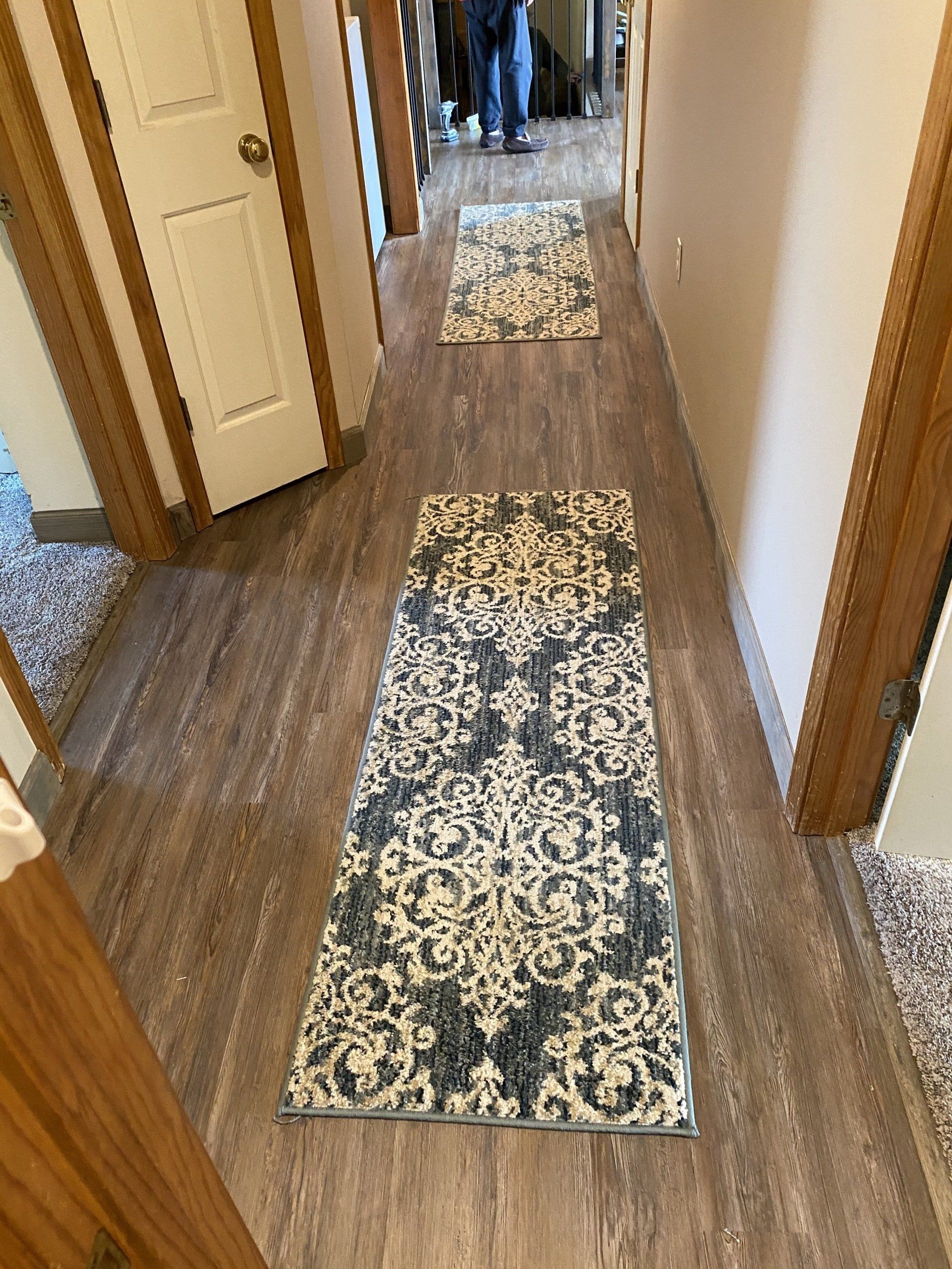 A hallway with hardwood floors and a rug on the floor.