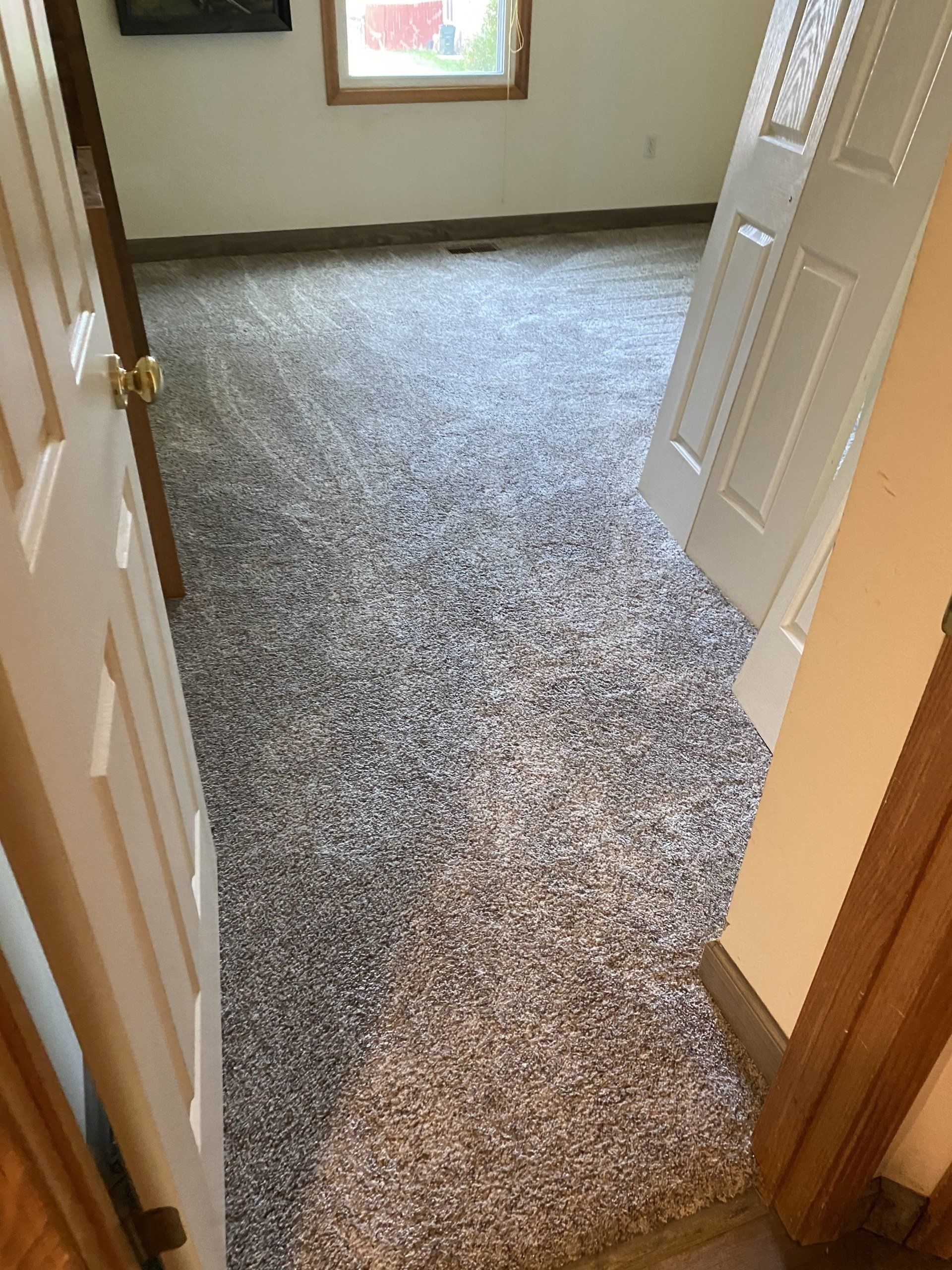 A room with a carpeted floor and a door leading to it.