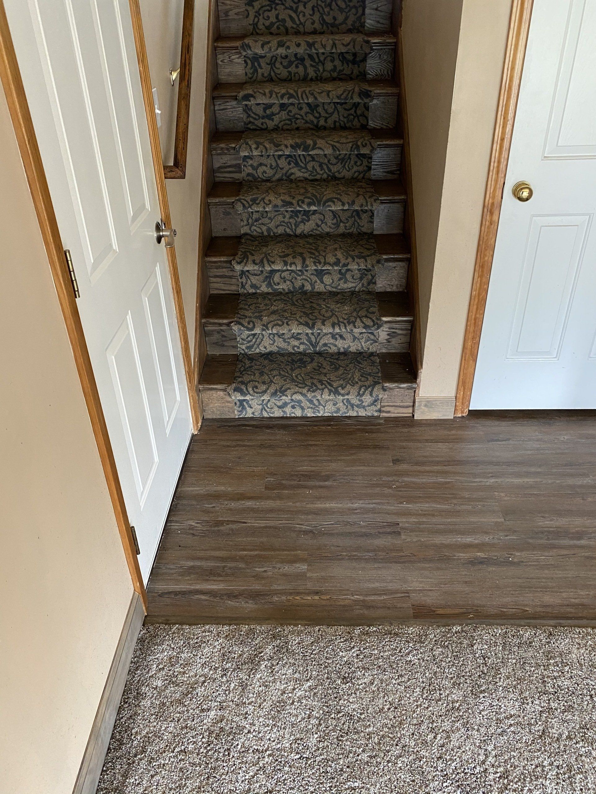 A hallway with stairs and a carpeted floor in a house.