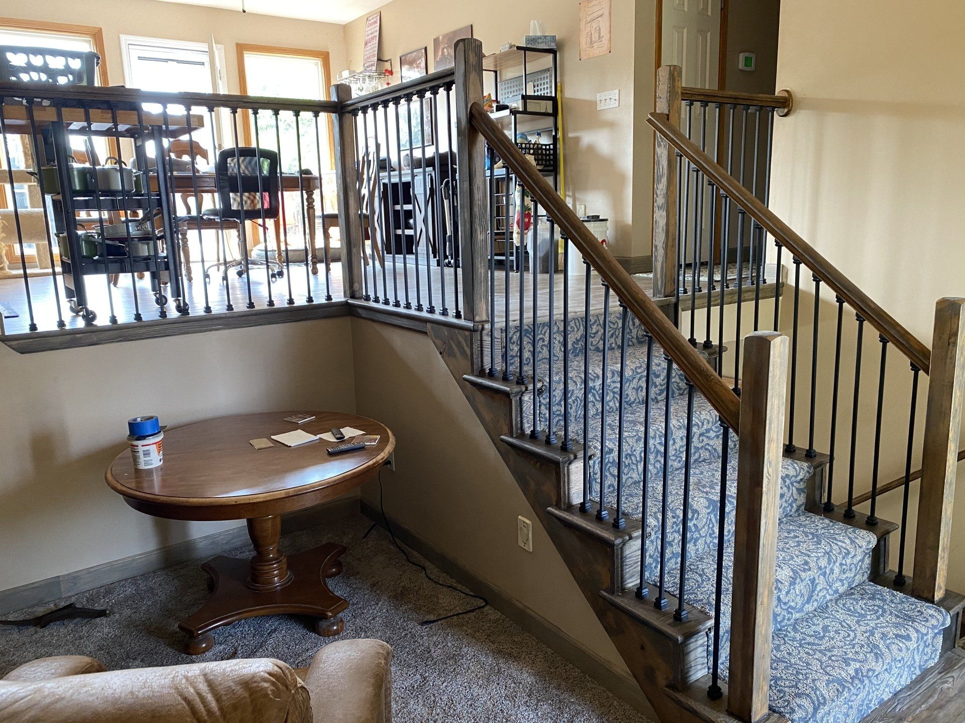 A living room with stairs leading up to the second floor and a table.
