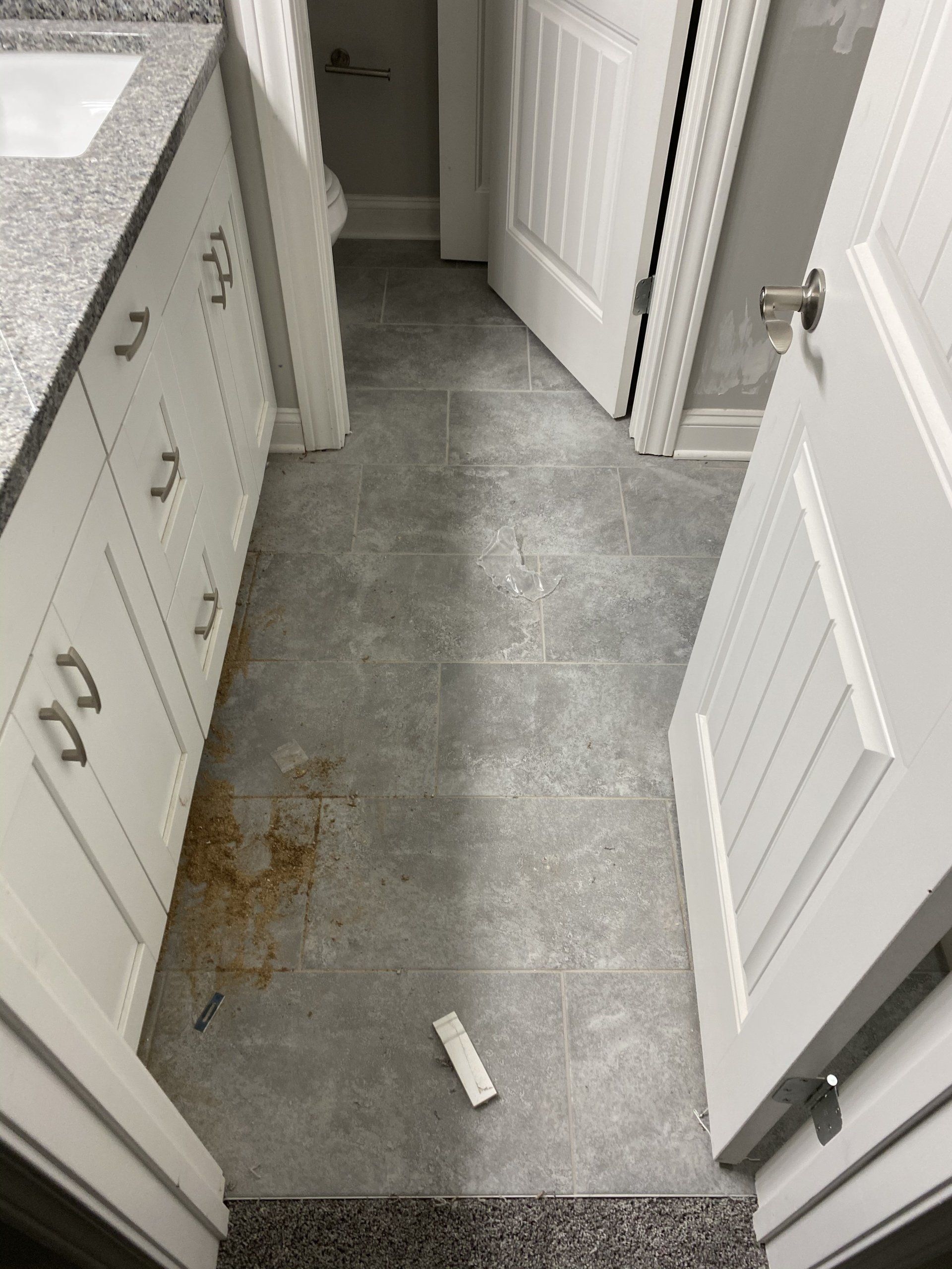 A bathroom with a dirty floor and white cabinets