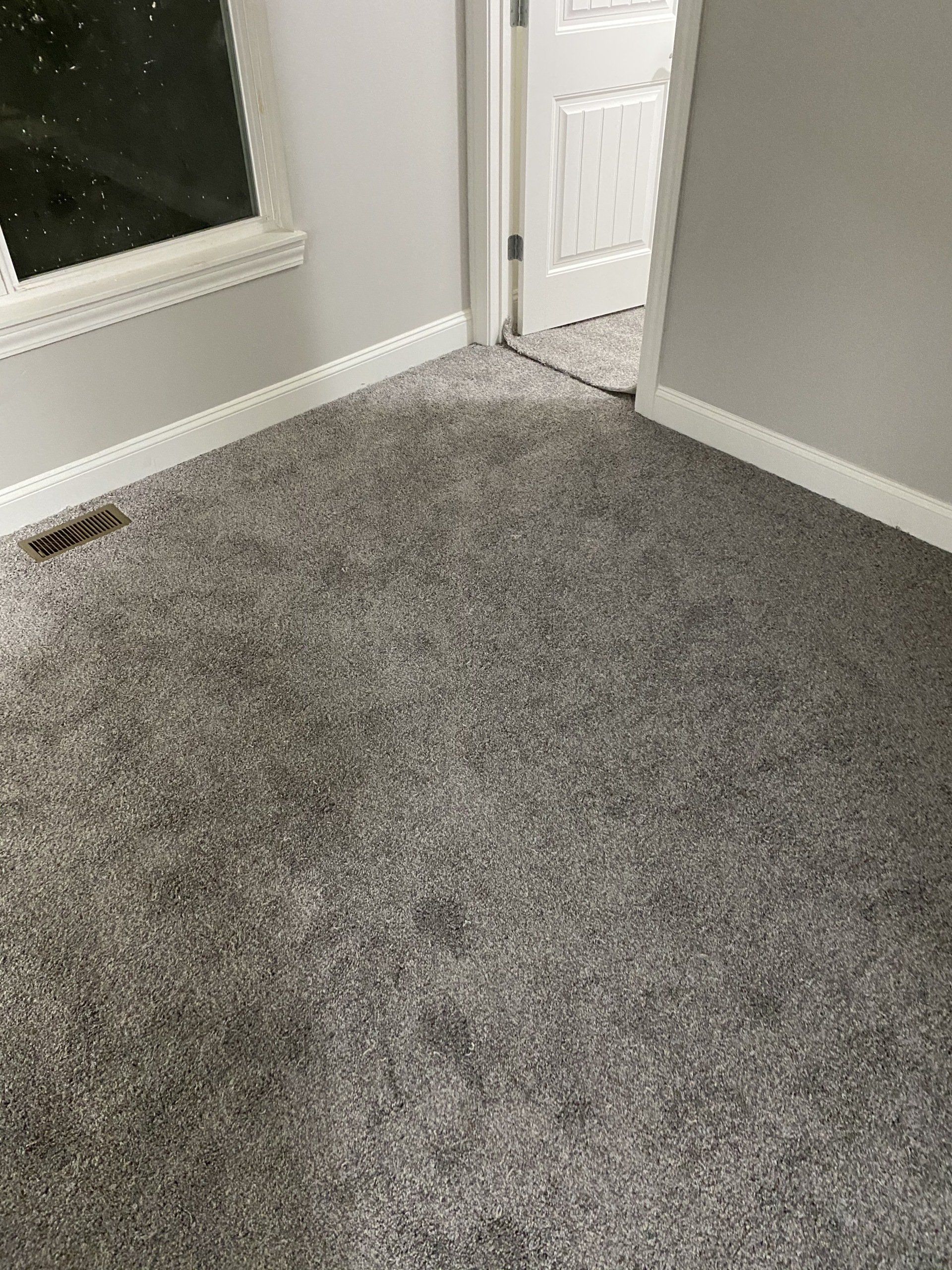 A room with a carpeted floor and a window.