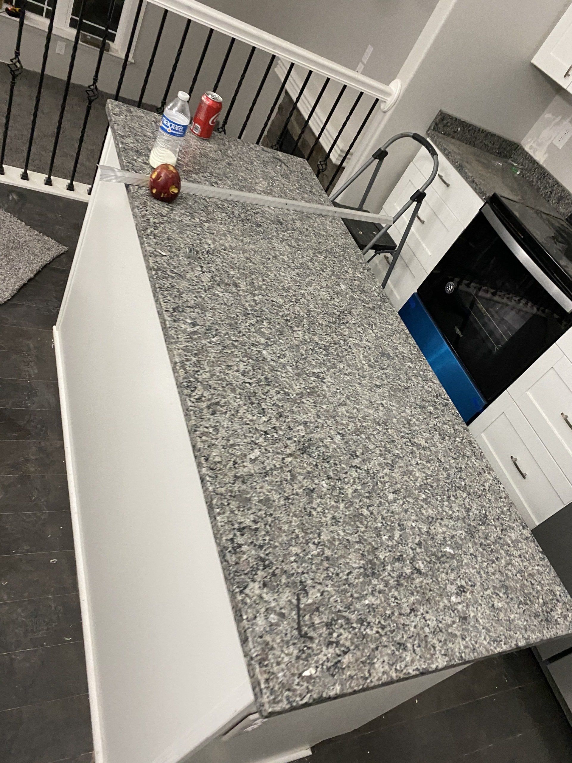 A kitchen with a granite counter top and white cabinets