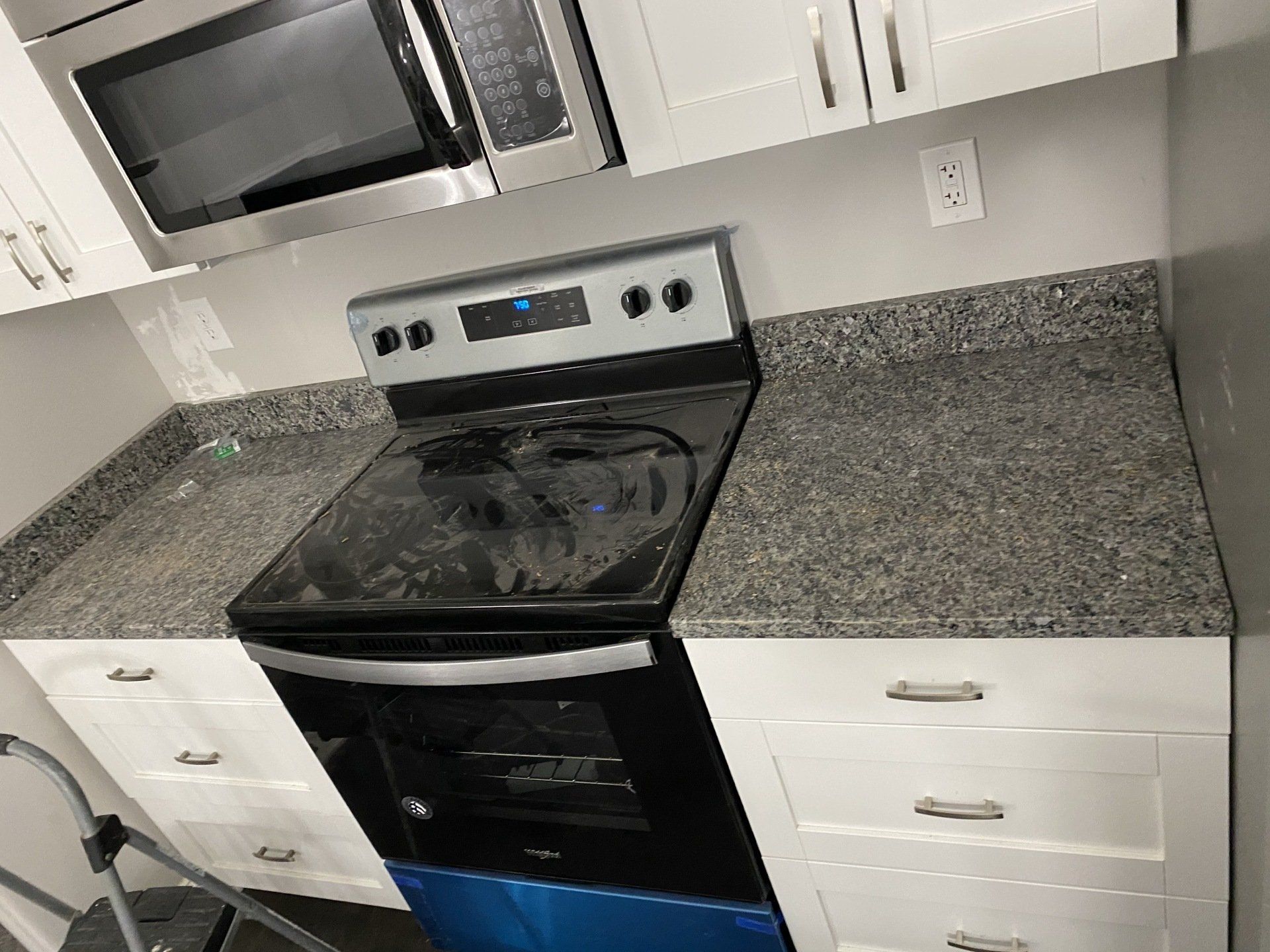 A kitchen with a stove , microwave , and granite counter tops.