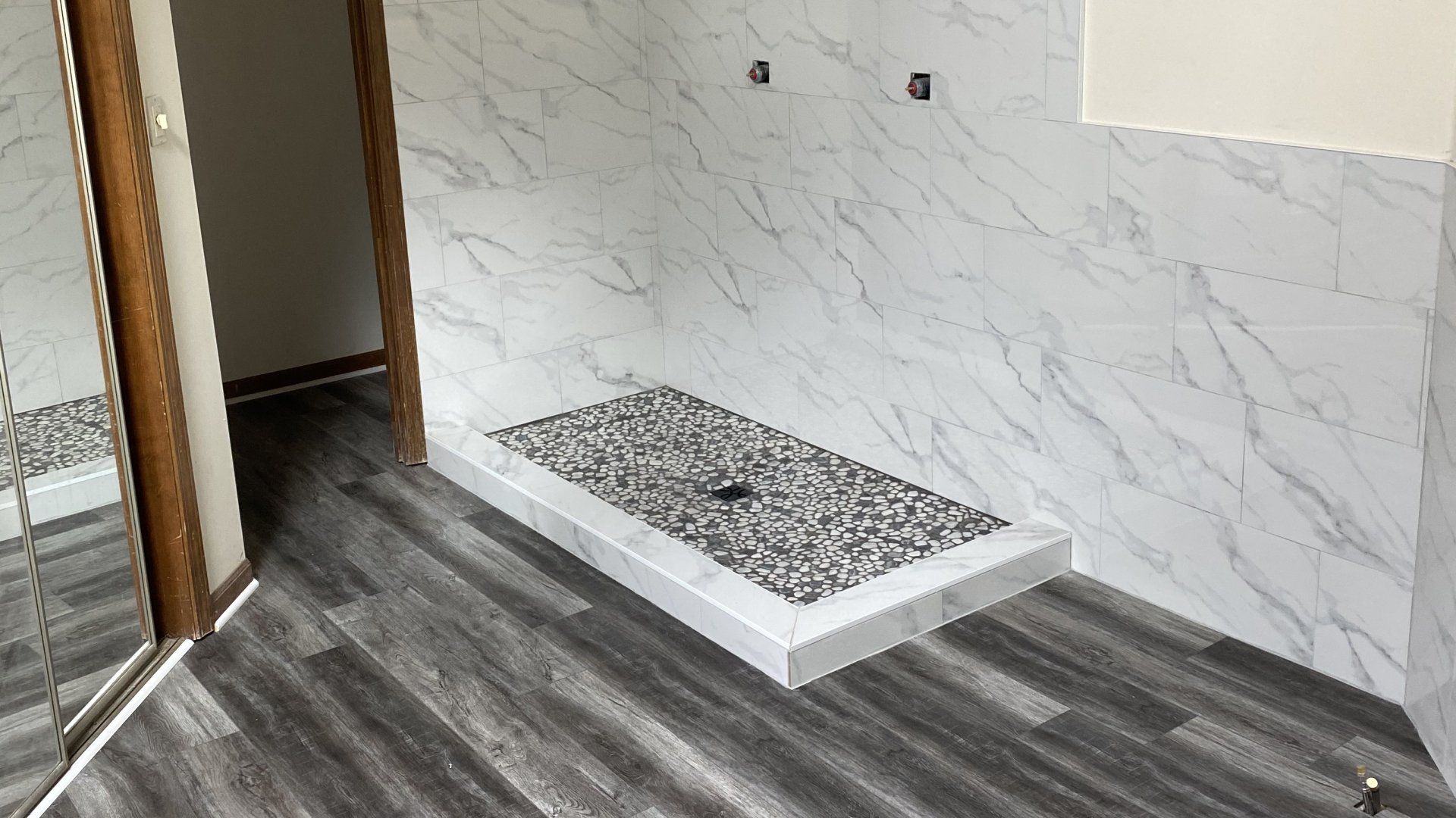 A bathroom with a walk in shower and a mirror.